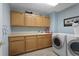 Functional laundry room featuring a sink, lots of counter space, wood cabinets, and front-loading washer and dryer at 11615 E Maplewood Ave, Englewood, CO 80111