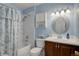 Bathroom showcasing a shower-tub combination with curtain, a vanity with a round mirror, and blue walls at 11644 Jackson St, Thornton, CO 80233