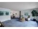 Bright living room with blue carpet, two chairs, side table, and artwork with dining area in the background at 11644 Jackson St, Thornton, CO 80233