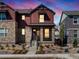 Two-story home with stone and red siding, welcoming front porch, and landscaping at dusk at 8115 Mt Harvard Rd, Littleton, CO 80125