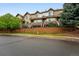 Townhome-style condominiums with brown siding and a brick retaining wall at street level with trees on either side at 5555 E Briarwood Ave # 2604, Centennial, CO 80122