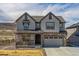 Beautiful two-story home with gray siding, stone accents, covered porch, and attached two-car garage at 3377 S Quartz St, Morrison, CO 80465