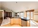 Kitchen island with wood cabinets, granite countertops, stainless steel dishwasher, and view of the living room and deck access at 23612 Glenmoor Dr, Parker, CO 80138