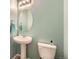 Powder room featuring a white pedestal sink, toilet, oval mirror, and modern fixtures at 277 Jewel St, Brighton, CO 80603