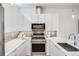A chef-inspired kitchen boasts sleek white cabinetry, stainless steel appliances, and backsplash at 3008 Blake St, Denver, CO 80205