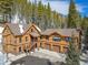Wood sided home with a two-car garage surrounded by wooded land and snow at 6087 Highway 9, Breckenridge, CO 80424