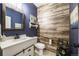 A stylish half bath with a modern vanity, decorative mirror, and unique wood-look accent wall at 12678 Fisher Ln, Englewood, CO 80112
