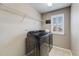Laundry room featuring modern washer and dryer units, storage shelves, and natural light from the window at 12678 Fisher Ln, Englewood, CO 80112