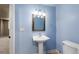 Powder room featuring blue walls, pedestal sink, an ornate mirror, and decorative lighting at 7099 Cerney Cir, Castle Pines, CO 80108