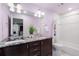 Bathroom featuring a double sink vanity with granite countertop and tub with white tile surround at 7099 Cerney Cir, Castle Pines, CO 80108