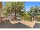 A view of a wooden deck with metal railings that overlooks mature trees and landscaping at 7099 Cerney Cir, Castle Pines, CO 80108