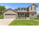 Charming two-story home with stone accents, a covered porch, an attached two-car garage and well-manicured lawn at 7099 Cerney Cir, Castle Pines, CO 80108