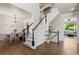 Open foyer with dark wood floors, view into dining and living rooms, and staircase with carpeted treads at 7099 Cerney Cir, Castle Pines, CO 80108