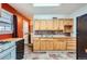 A kitchen with light wood cabinets, a stainless-steel sink, and tile flooring, adjacent to a door leading to the laundry area at 1931 Dayton St, Aurora, CO 80010