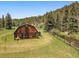 Exterior view of a rustic wooden barn surrounded by trees and a split rail fence at 32453 Upper Bear Creek Rd, Evergreen, CO 80439