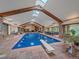 Indoor pool area featuring exposed beams, skylights, an attached diving board, and dining area at 32453 Upper Bear Creek Rd, Evergreen, CO 80439