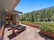 Outdoor patio with chaise lounges and views of a green, tree-covered landscape at 32453 Upper Bear Creek Rd, Evergreen, CO 80439