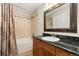 Bathroom with a shower over the tub, earth-tone tiling, and a dark granite vanity at 8643 Gold Peak Dr # E, Highlands Ranch, CO 80130