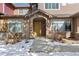 Inviting home entrance featuring a stone archway and tasteful landscaping; snow on ground at 8643 Gold Peak Dr # E, Highlands Ranch, CO 80130
