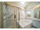 Well-lit bathroom featuring a glass-door shower, jacuzzi tub, tiled walls, and a built-in skylight at 12663 S Silver Creek Ct, Parker, CO 80134