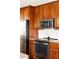 Close-up view of kitchen with stainless steel oven, microwave, refrigerator, wood cabinets and white subway tile at 6385 S Jay Way, Littleton, CO 80123