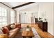 Cozy living room featuring hardwood floors, a leather sofa, and large windows with natural light at 6385 S Jay Way, Littleton, CO 80123