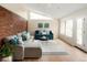 Relaxing living room with brick feature wall, modern furniture, and ample natural light at 6385 S Jay Way, Littleton, CO 80123