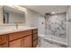 Updated bathroom featuring a marble floor, cherry vanity, shower with decorative accent wall and modern fixtures at 575 N Marion St, Denver, CO 80218