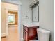 Bathroom with cherry vanity, decorative mirror and lighting, a toilet, and view of an adjacent room at 575 N Marion St, Denver, CO 80218