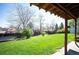 Spacious backyard with lush green lawn, mature trees, privacy fence, and covered patio at 4360 S Braun Ct, Morrison, CO 80465