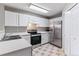 Kitchen featuring white cabinetry, stainless steel appliances, and neutral tile flooring at 2575 S Syracuse Way # 101, Denver, CO 80231