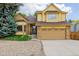 Two-story home featuring a front-facing two-car garage, brick and shingle siding, and lush landscaping at 12319 W Burgundy Ave, Littleton, CO 80127