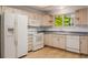 Bright kitchen featuring wood floors, white appliances, wood cabinets and a window overlooking the yard at 12319 W Burgundy Ave, Littleton, CO 80127