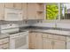 An open kitchen with a white stove, microwave, and a kitchen sink under a window at 12319 W Burgundy Ave, Littleton, CO 80127