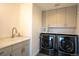Well-equipped laundry room featuring modern washer and dryer, storage cabinets, and a utility sink at 3600 N Pecos St, Denver, CO 80211