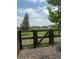 A weathered wooden fence and gate provide a charming entrance with a grassy area and neighborhood views beyond at 5226 Inland Ave, Firestone, CO 80504