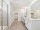 Ensuite bathroom features double sink vanity, framed mirrors, tiled shower, and walk-in closet access at 5226 Inland Ave, Firestone, CO 80504