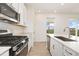 White kitchen boasts stainless steel appliances, quartz countertops, a sink with a window view, and light wood flooring at 5226 Inland Ave, Firestone, CO 80504