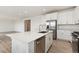 Kitchen features white cabinets, stainless steel appliances, quartz countertops, large island, and light wood flooring at 5226 Inland Ave, Firestone, CO 80504