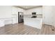 Bright kitchen featuring white cabinets, stainless steel appliances, large island, and light wood flooring at 5226 Inland Ave, Firestone, CO 80504
