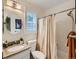 Well-lit bathroom featuring granite counters, a round mirror, and a shower-tub with a neutral shower curtain at 11275 Holly St, Thornton, CO 80233