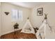 Bright, airy bedroom showcasing two play tents, a lush plant, and rich hardwood floors at 11275 Holly St, Thornton, CO 80233