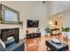 Bright living room featuring hardwood floors, a fireplace, a large mirror, and a mounted TV at 11275 Holly St, Thornton, CO 80233