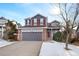 Two-story house with gray siding, red brick accents, and a two-car garage at 3836 Garnet Way, Highlands Ranch, CO 80126