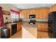 Kitchen with light wood cabinets, dark countertops, and black appliances at 3836 Garnet Way, Highlands Ranch, CO 80126