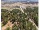 An aerial view showcases the home nestled amongst the trees with easy access to roads and nearby areas at 4185 Red Rock Dr, Larkspur, CO 80118