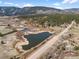 An aerial view showcases the landscape with ponds and a view of the home in a wooded community at 4185 Red Rock Dr, Larkspur, CO 80118