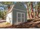 A storage outbuilding with double doors is painted green to blend in with its wooded surroundings at 4185 Red Rock Dr, Larkspur, CO 80118