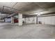 Well-lit parking garage with concrete pillars, yellow lines, visible pipes, and cars parked in designated spots at 340 S Lafayette St # 204, Denver, CO 80209