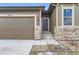 Exterior view of home with two-car garage, stone accents, and covered front entry at 6712 Sea Oats Dr, Parker, CO 80138